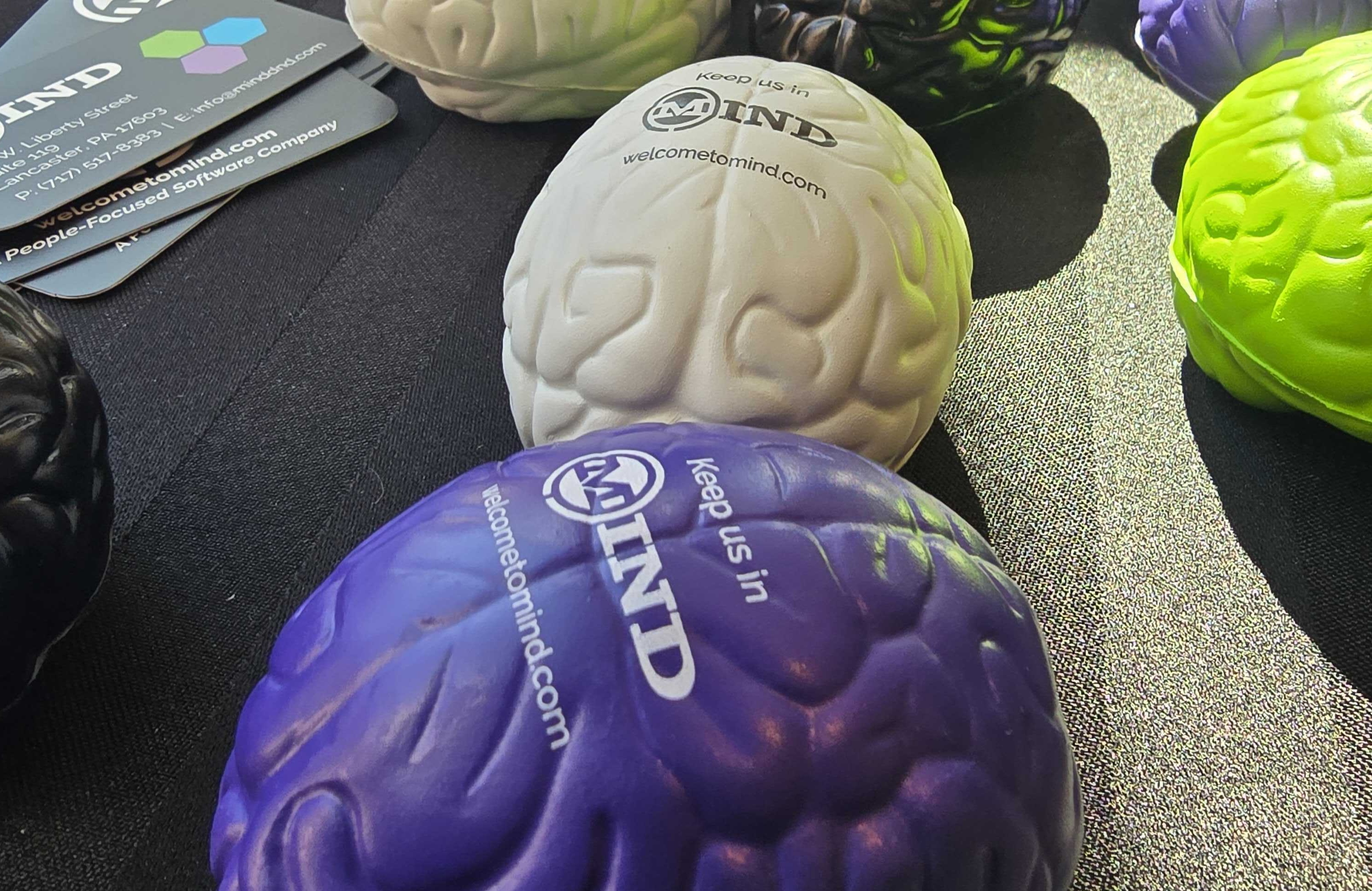 Photo showing a table full of squishable brain stress toys with the Mind company branding