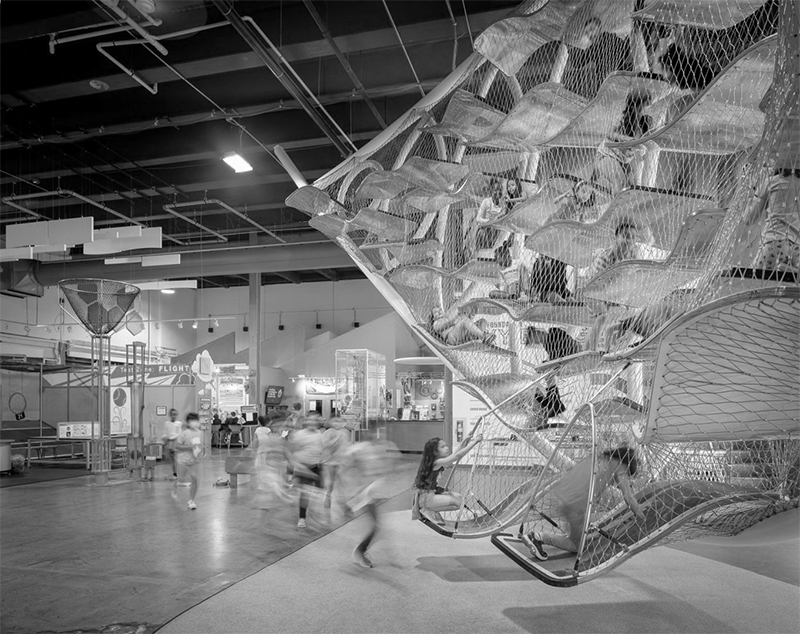 Visitors exploring a large climbing net exhibit