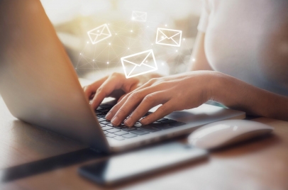 closeup of woman using laptop with email icons superimposed on top of the image