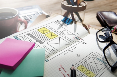notebook with sketch of website layout next to post-its and glasses