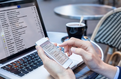 businessperson checking email on phone and laptop