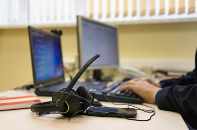 headset on a desk with a person typing on a laptop