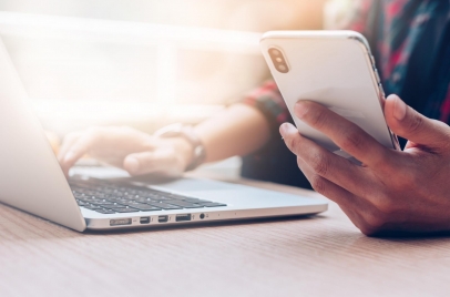 man using a laptop and phone for online meeting