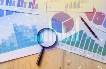 graphs and charts on a desk with a magnifying glass and a pen