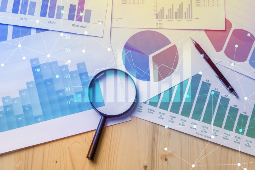 graphs and charts on a desk with a magnifying glass and a pen