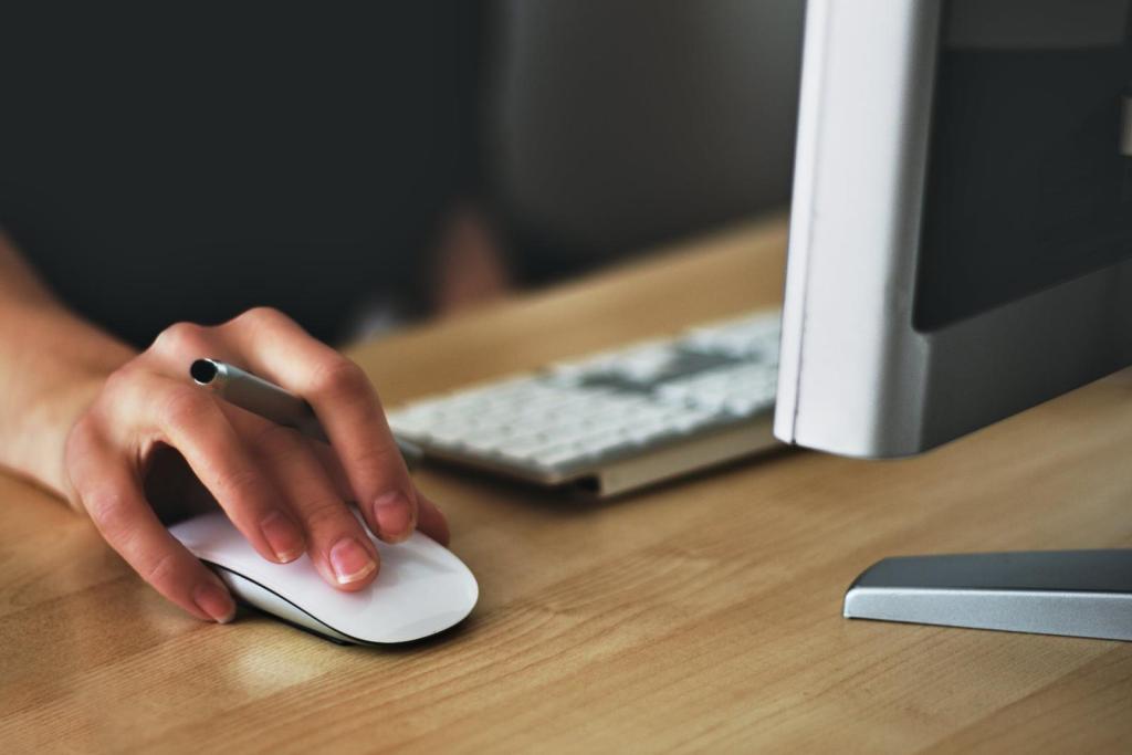 A close-up photo of a person’s hand holding a white Apple mouse