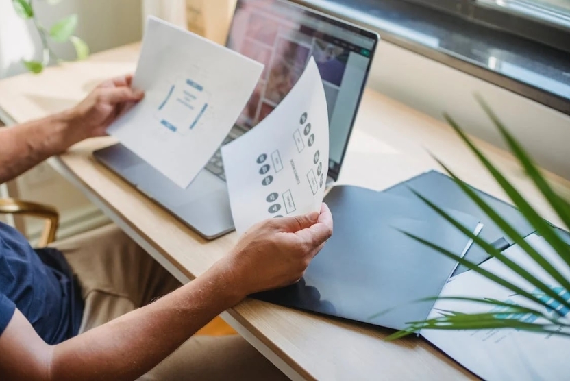 A person working on a laptop, reviewing different minimalistic web design blueprints