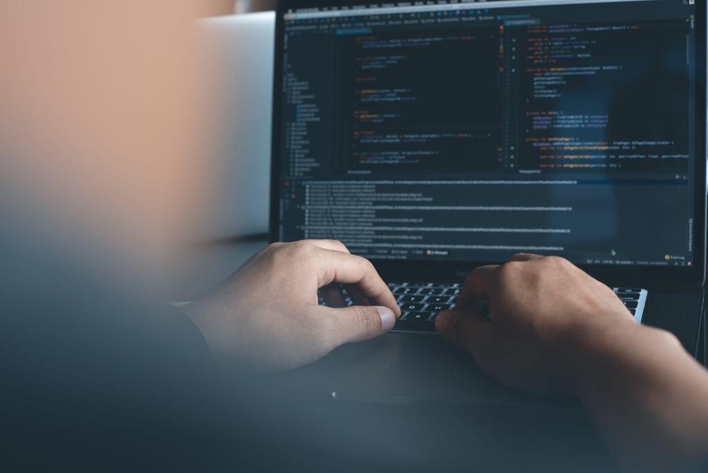person typing on a laptop, coding an application